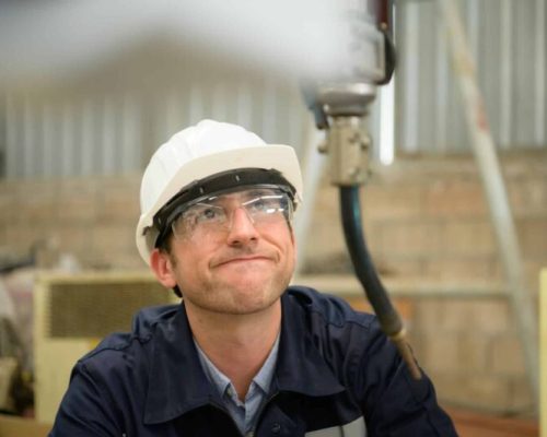 Young male engineers with experience are maintaining and testing the functionality of welding robots